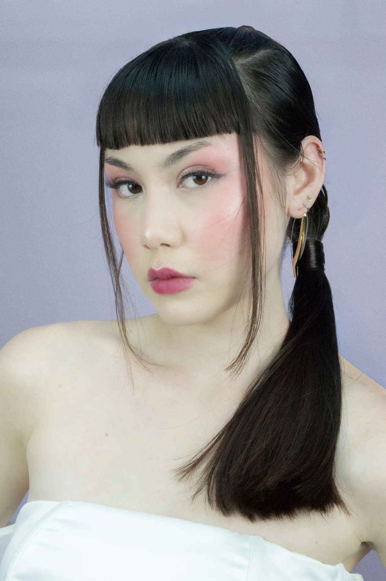 Editorial portrait with a dark fringe and graphic makeup.