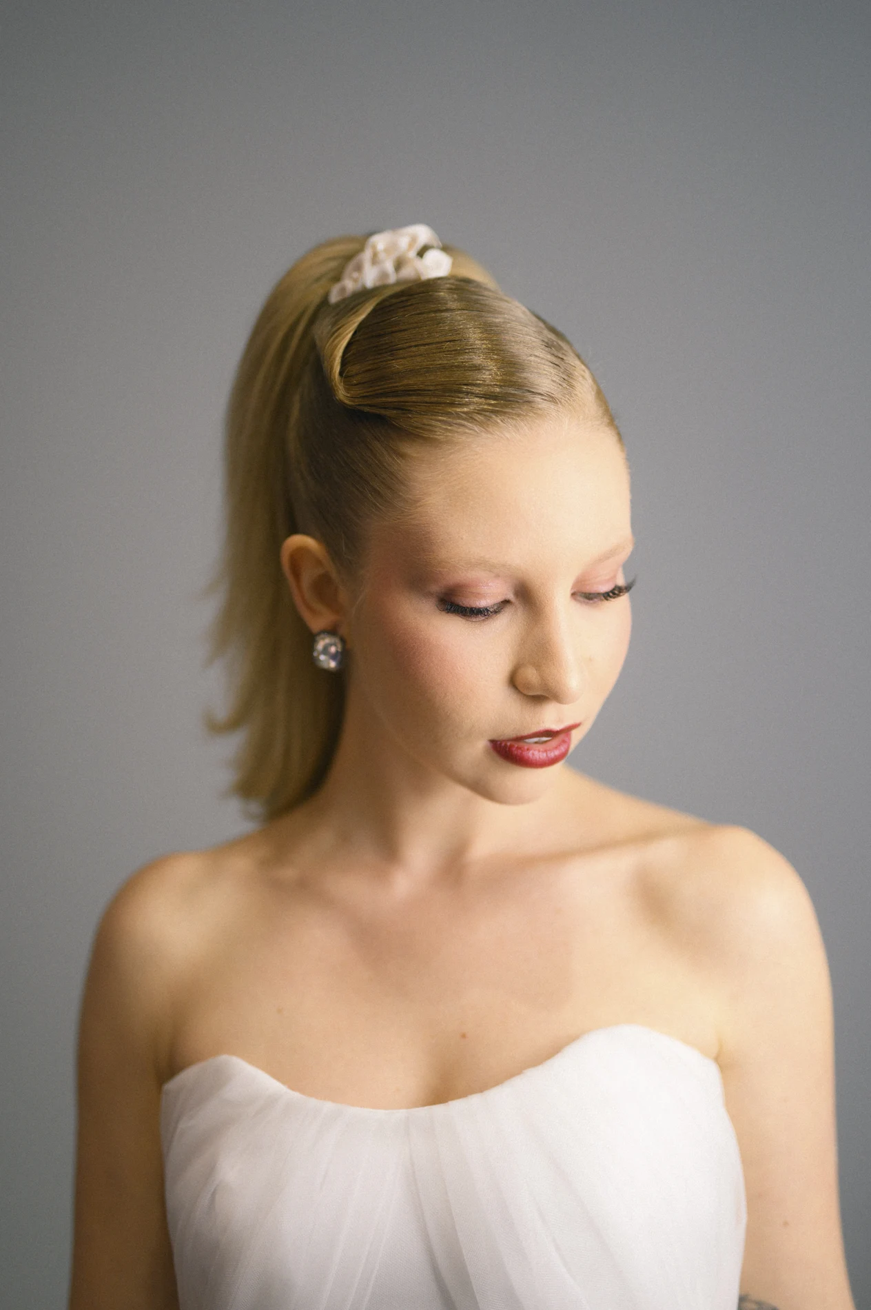 Soft makeup and a high updo photographed against a gray background.