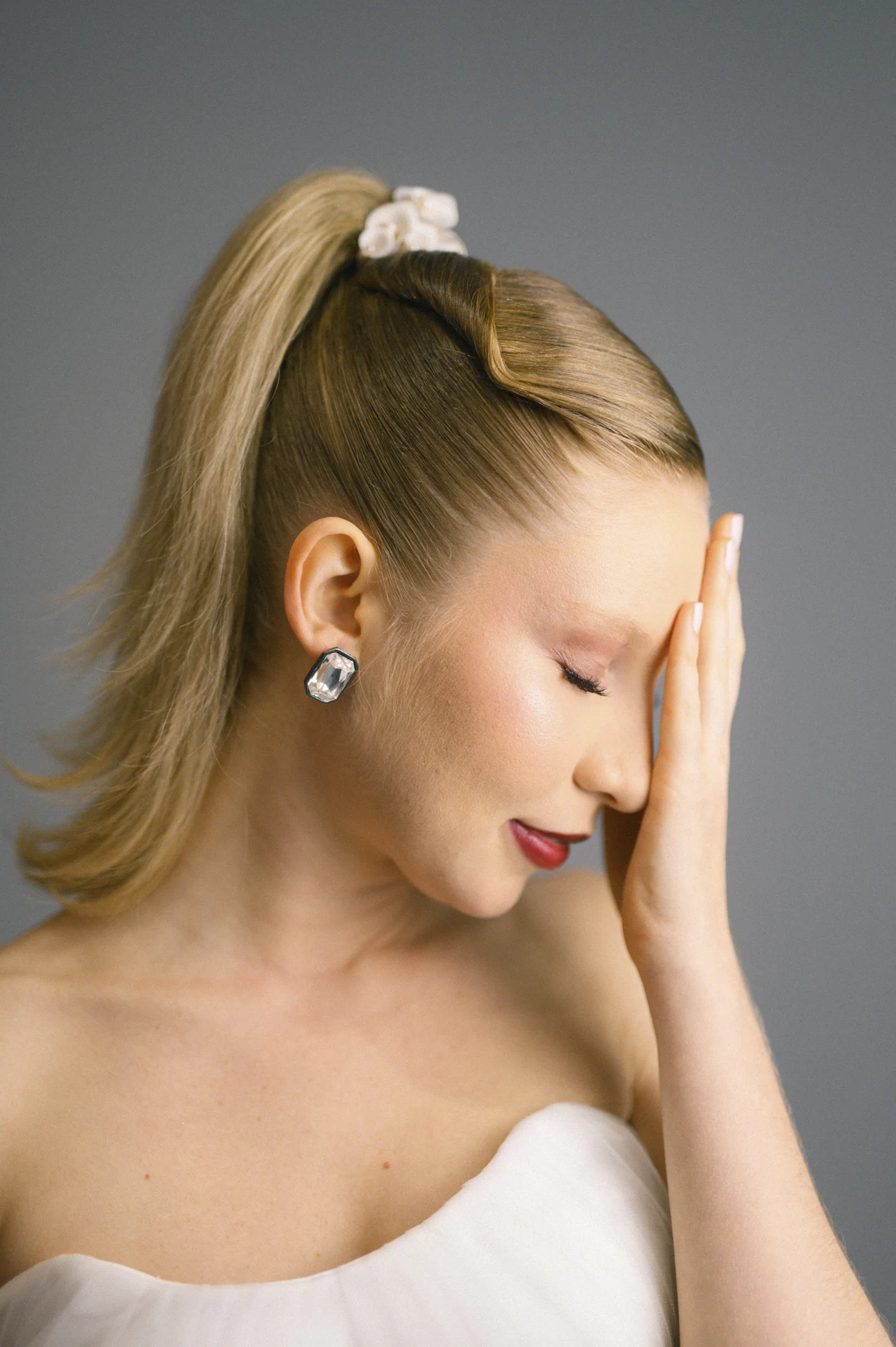 Luminous skin, a deep lip color, and a high ponytail in profile.