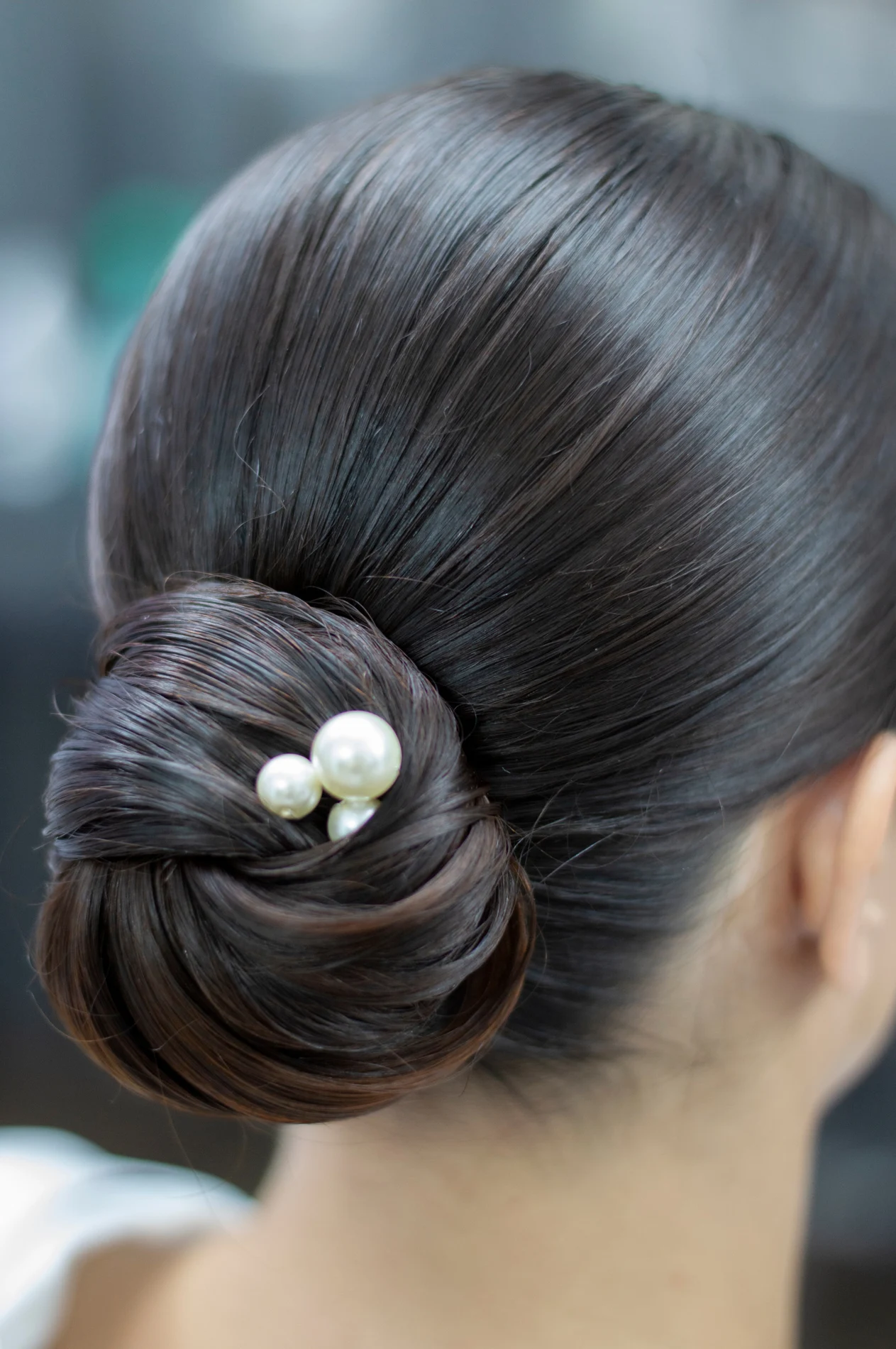 Rear view of a low bun finished with a small pale accessory.