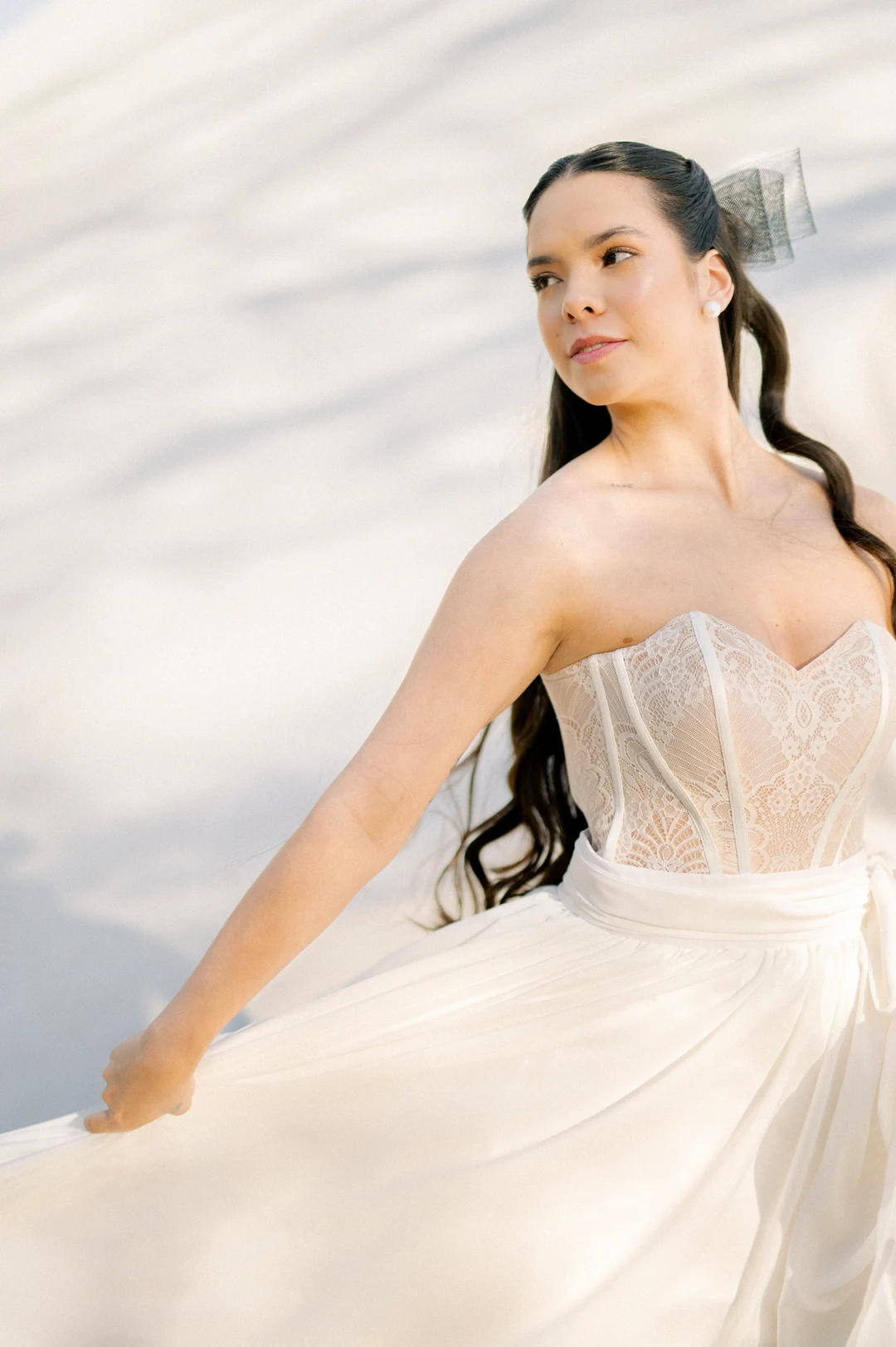 Bride with long dark hair and a structured white dress.