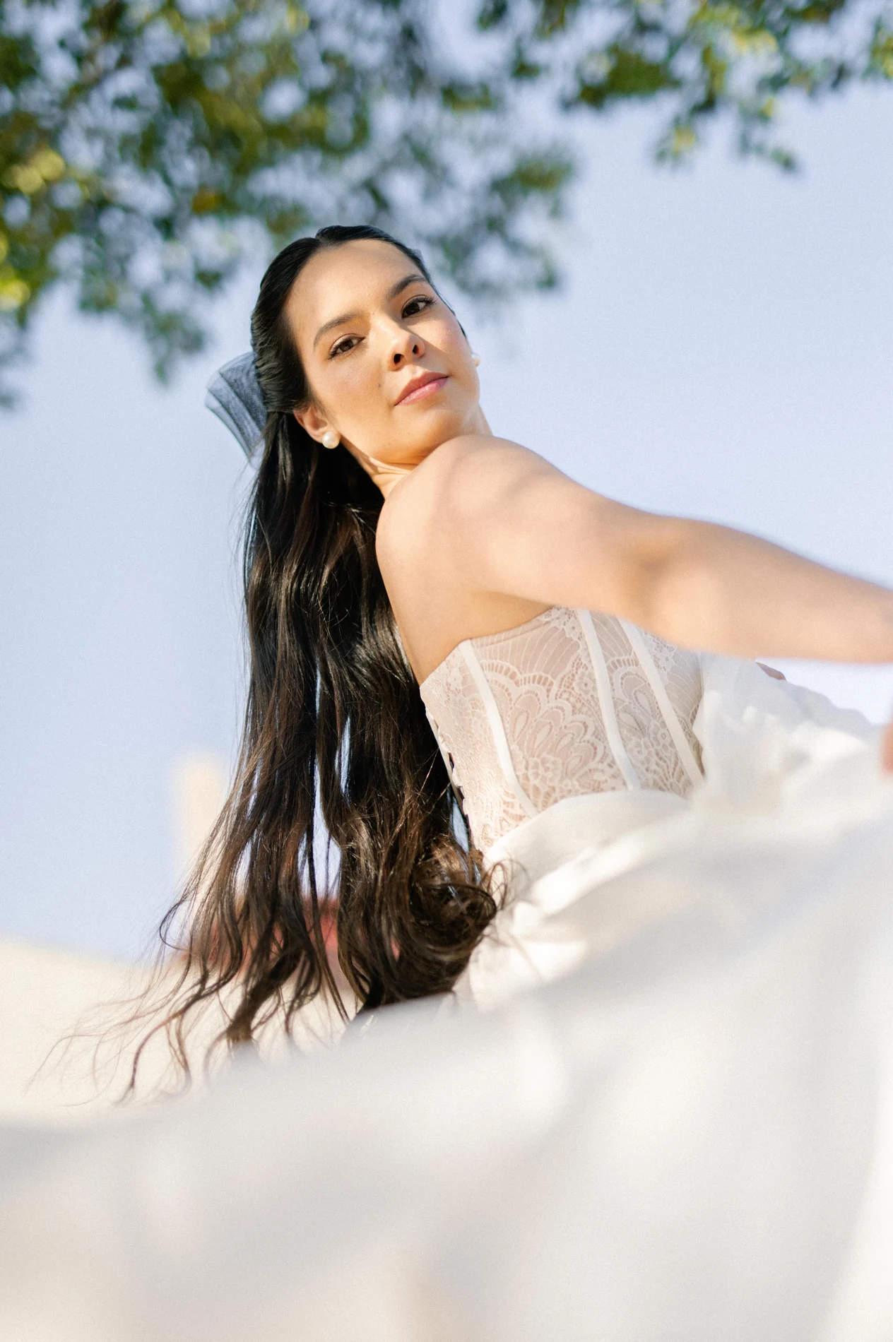 Bride with long hair and a white dress photographed outdoors.