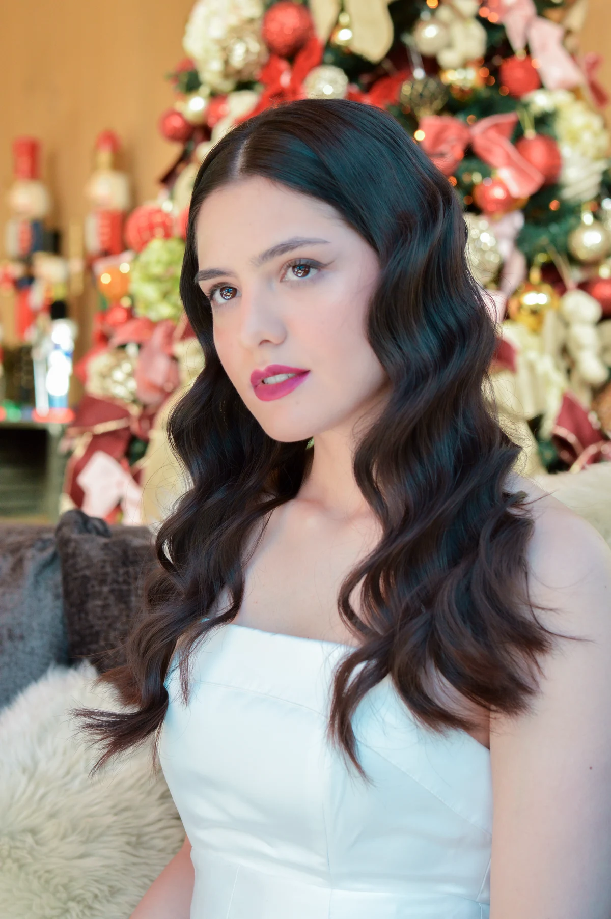 Portrait with dark wavy hair in front of flowers.