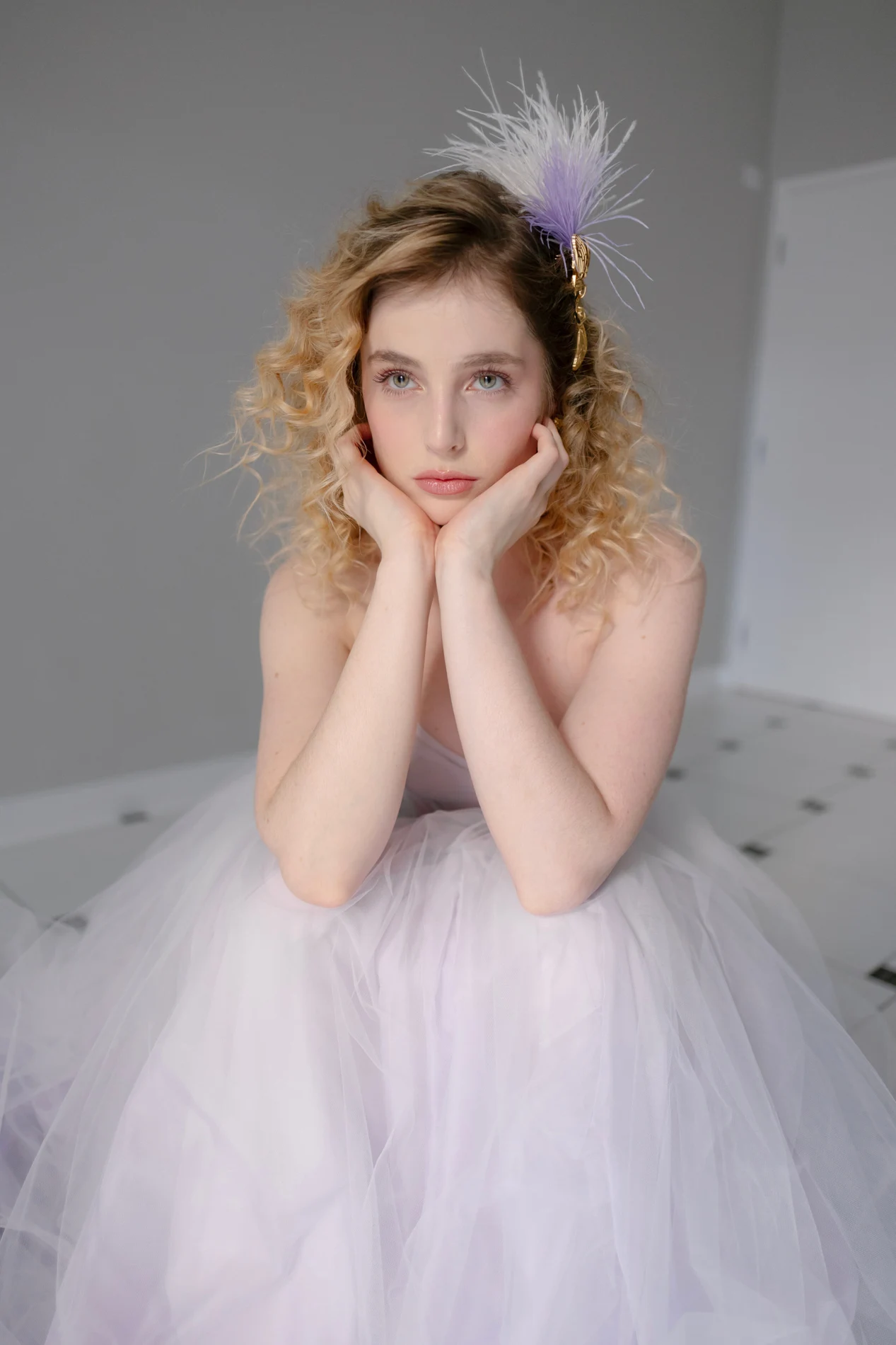 Blonde beauty portrait with hands near the face and a pale dress.